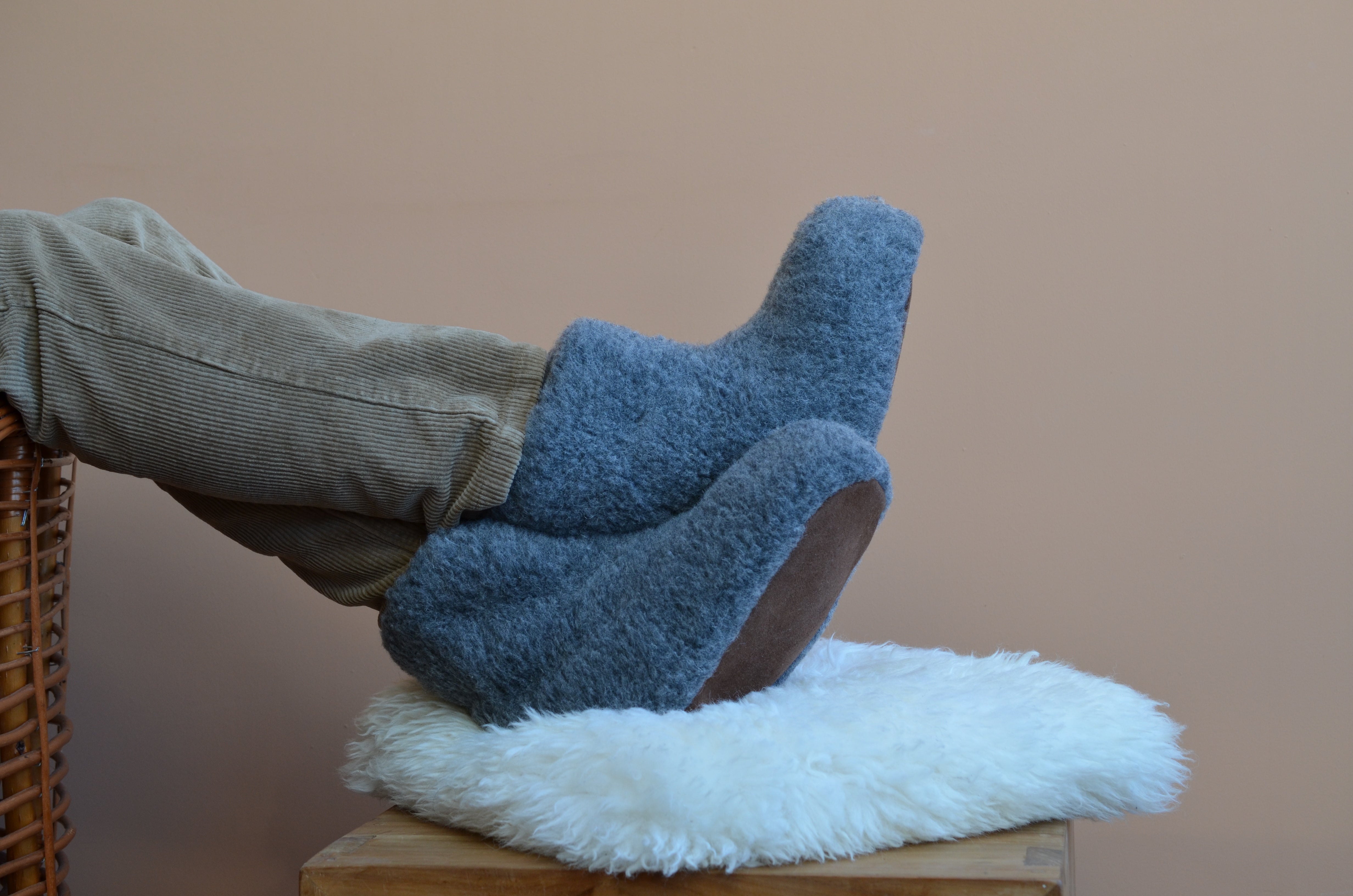 Mann legt Hausschuhe aus Wolle auf ein weißes Lammfell - Wollbebi