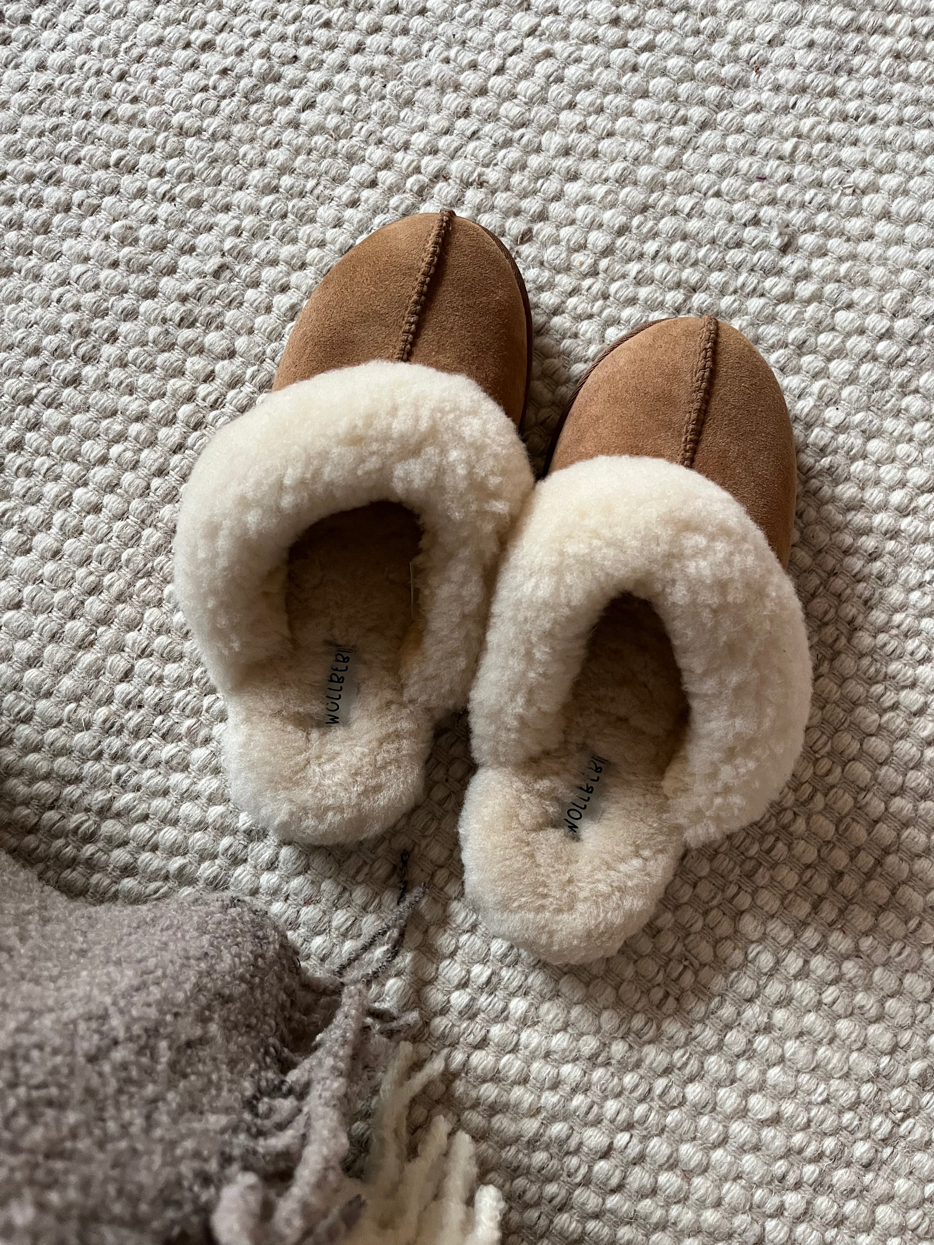 kuschelige lammfellpantoffeln cognac auf Wollteppich