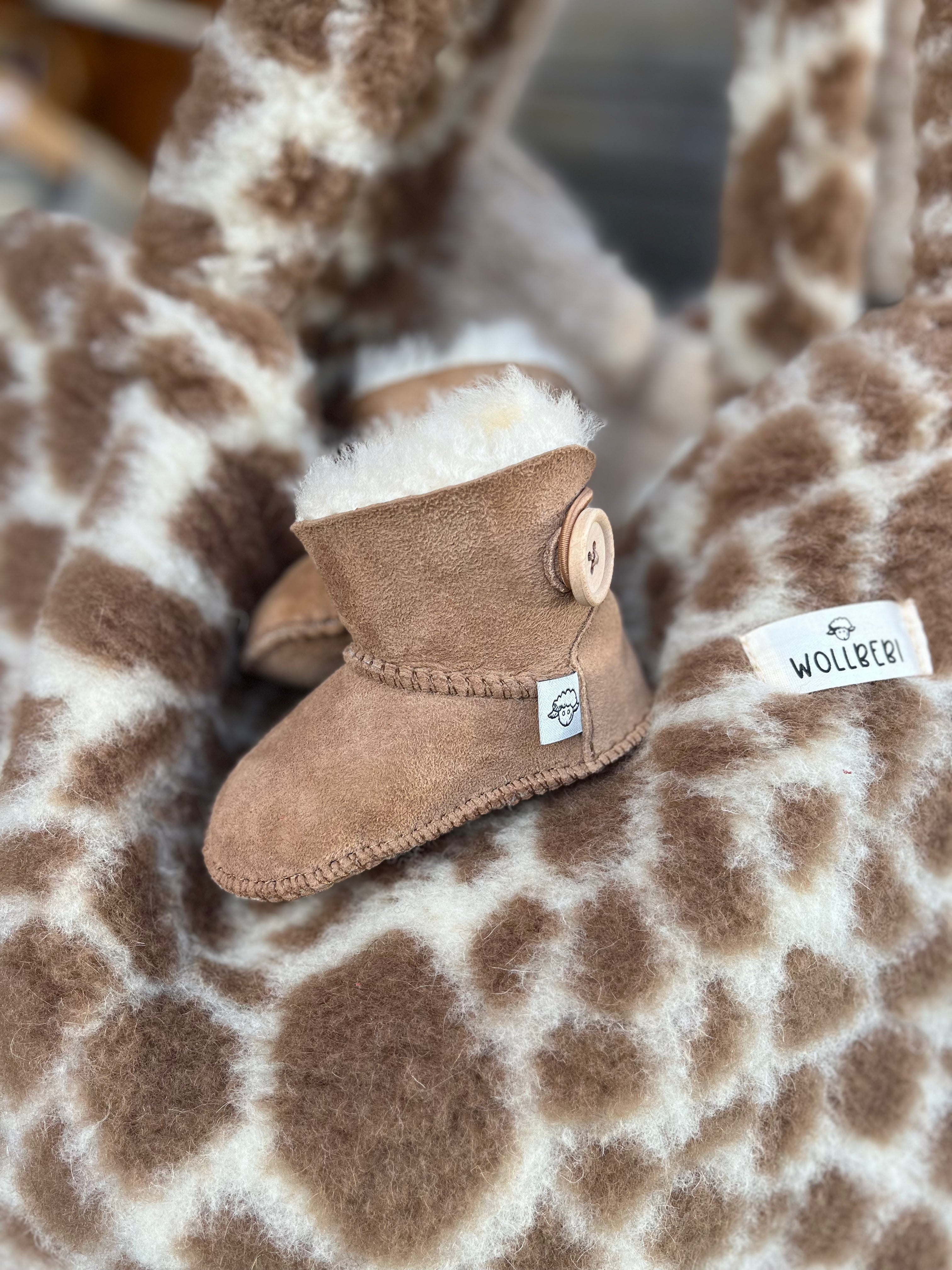 Braune Lammfell-Hausschuhe für Baby liegen auf Wolltasche - Wollbebi