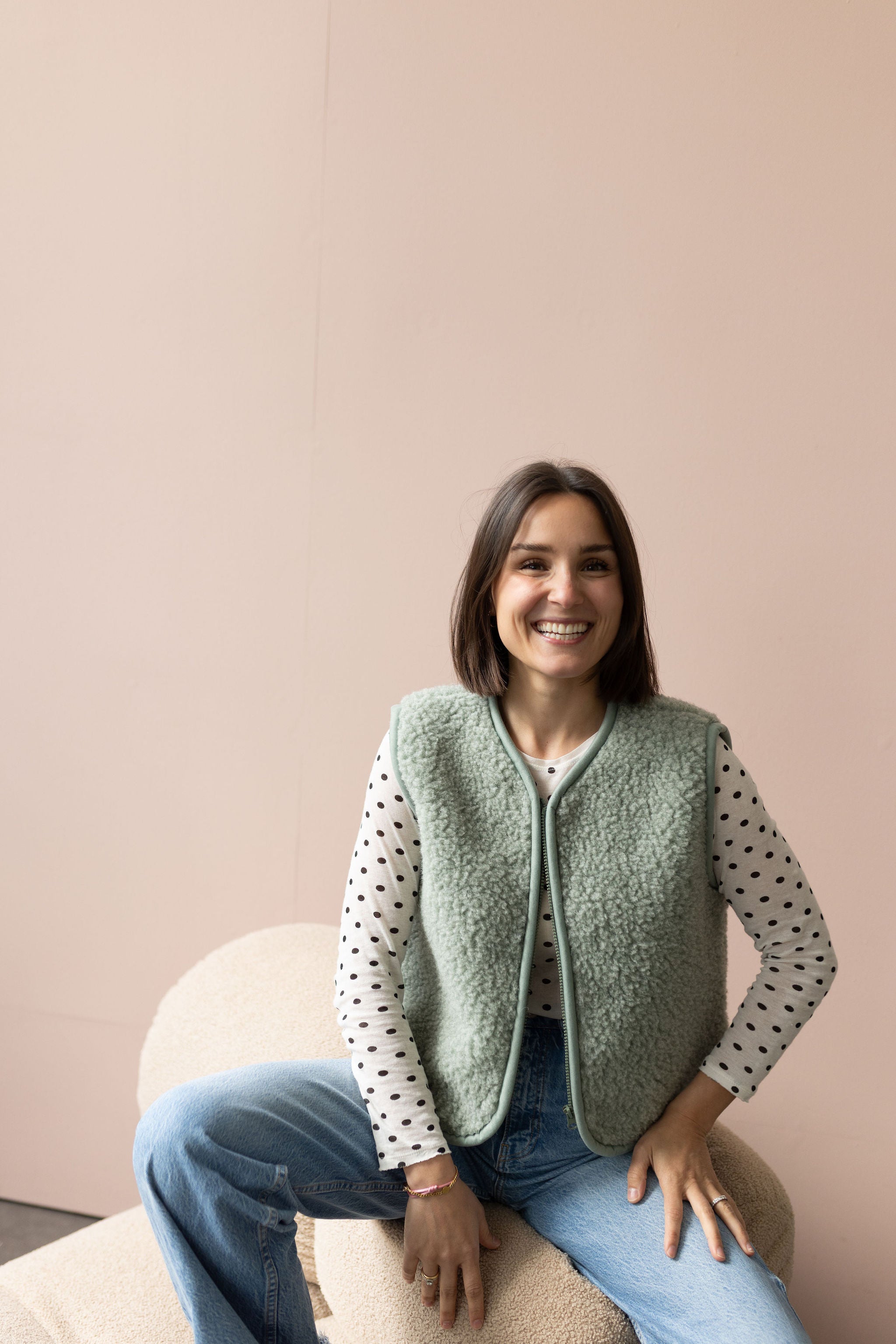 Frau in lila Wollweste hält ein Kind in kurzer dunkler Wollweste - Wollbebi